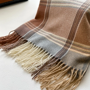 Close-up of soft plaid scarf with fringe detail in warm earth tones and tassel edge