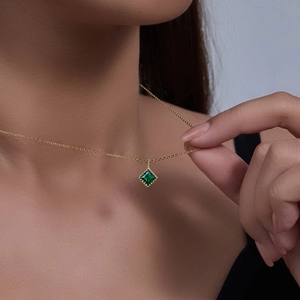 Detailed close-up of emerald green square zircon pendant necklace on a gold metal chain