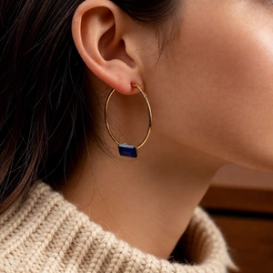 Detail view of large 24k gold-plated hoop earrings with a rectangular blue gemstone