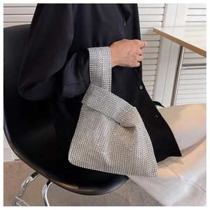 Close-up of sparkling silver rhinestone evening handbag with a ring handle on a model