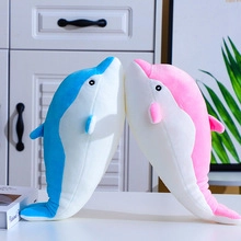 Close-up of blue and pink plush dolphins kissing on a table for a romantic gift