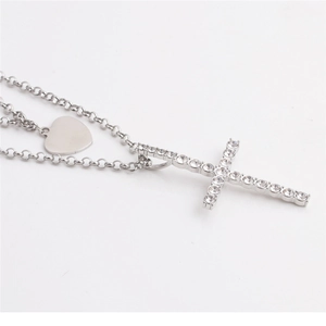 Detail of silver double layer necklace with polished heart tag and rhinestone cross pendant