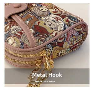 Detail of pink leather edging and golden hardware hooks on a bear jacquard bag