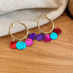 Detail of bohemian gold hoop earrings with colorful dangles on burlap background