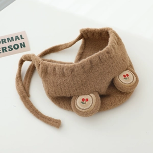 Détail d'un bonnet en peluche marron pour bébé avec cerise brodée et oreilles d'ours