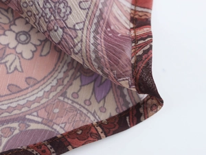 Dettaglio macro del tessuto in chiffon con stampa paisley rosa e viola e cuciture fini