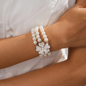 Close-up of a multi-layer faux pearl bracelet with a sparkling silver clover diamond clasp