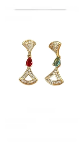 Macro view of 14K gold plated fan-shaped earrings with red and green drop stones