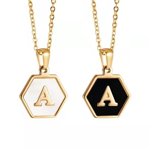 Detalle de colgantes hexagonales de nácar con letra A dorada en collares de acero