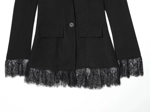 Detailed view of black blazer showing lace patchwork hem and resin button closure
