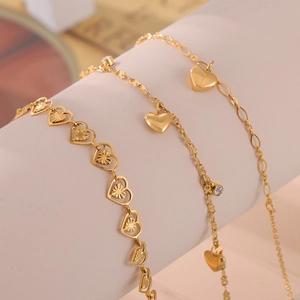 Set of three gold heart anklets with zircon accents displayed on a jewelry stand