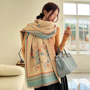 Beige winter shawl with vintage blue and orange floral pattern in cozy indoor setting