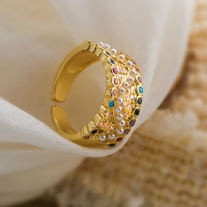 Detailed close-up of gold geometric ring with colorful zircons and white pearls