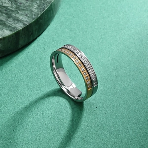 Titanium steel ring with silver base, gold edges and zircon inlay on green marble background