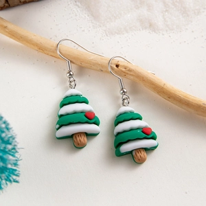 Close-up of resin Christmas tree earrings with white snow and red heart on wood branch