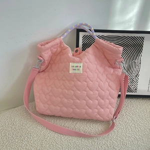 Detail van roze gewatteerde canvas tas met hartpatroon en gestreept handvat