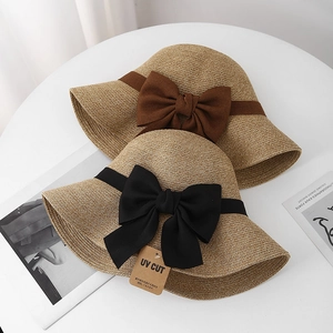 Detail of woven straw hats with large decorative bows and UV protection label