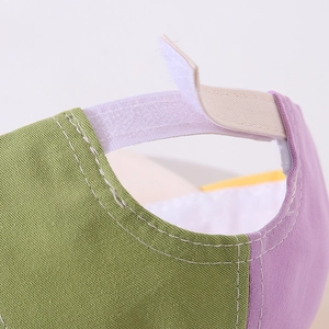 Detail view of the adjustable hook-and-loop strap on a purple and green baby baseball cap