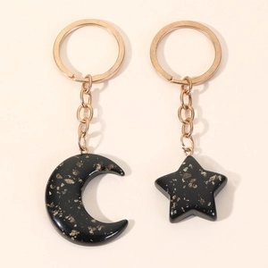 Star and moon resin keychain set with gold foil flakes on beige background