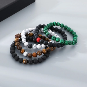 Close-up of stacked beaded bracelets with tiger eye, white turquoise, and black lava stones