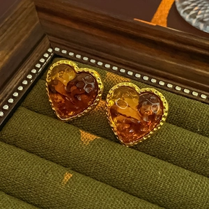 Detailed view of heart-shaped amber resin earrings with golden beaded metal borders