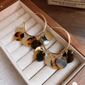 Retro golden hoop earrings with leopard resin and metallic discs on velvet display