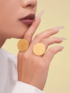Gros plan de bagues rondes plaquées or portées par un mannequin pour un look vintage chic