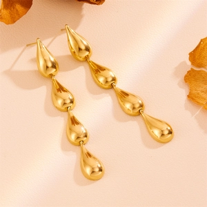 Close-up of golden teardrop earrings with mirror polished finish and layered metal design