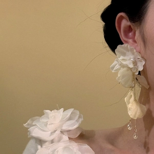 Detailed view of elegant white fabric jasmine flower tassel earrings worn by a model.