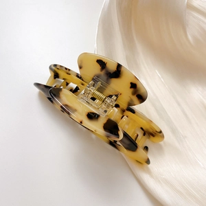 Minimalist acetate crescent hair claw with tortoise shell pattern on silk background