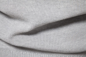 Macro shot of light gray men's sweater showing fine ribbed knit fabric and soft texture
