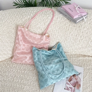 Detailed view of quilted satin tote bags with bow accents in soft pink and light blue colors
