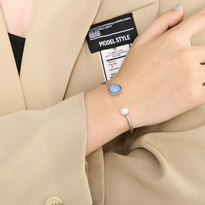 Détail du bracelet ouvert en acier titane argenté avec cristal bleu et perle blanche