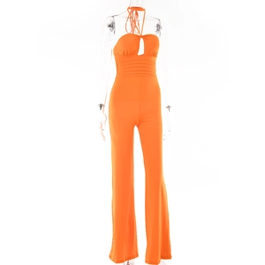 Detail of orange halter neck jumpsuit featuring chest cutout and waist pleats on wide leg pants