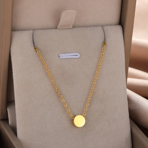 Detail of gold geometric round pendant necklace showcased in a beige velvet jewelry box