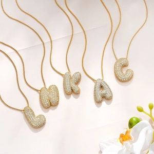 18K gold plated initial necklaces with crystal zircon alphabet pendants on pink background