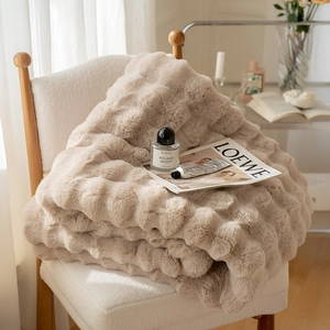 Detail of plush faux fur blanket with wave texture folded on a modern white fabric chair