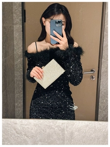 Close-up of golden wave pattern clutch bag held by model wearing a feathered sequin dress