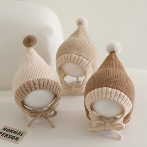 Detailed knit texture of color-block baby wizard hats with pom-poms and earflaps