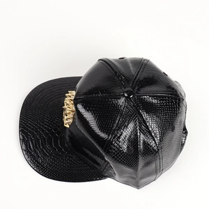 Macro view of black faux-crocodile leather texture and gold crown ornament on the cap