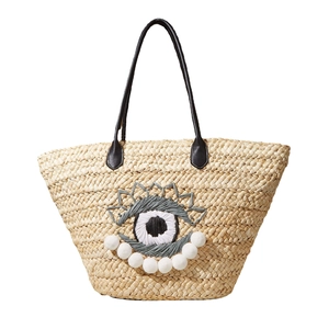 Sac de plage en paille de maïs avec motif oeil brodé et détails de pompons