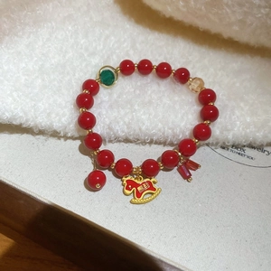 Dettaglio del bracciale di perle di agata rossa con ciondolo a cavallo dorato