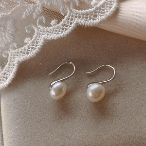 Elegant pearl drop earrings on beige velvet with lace detail and silver hooks