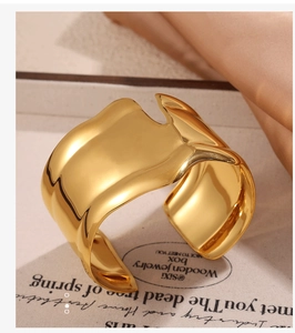 Close-up of irregular gold cuff bracelet with high-shine metallic finish in warm light