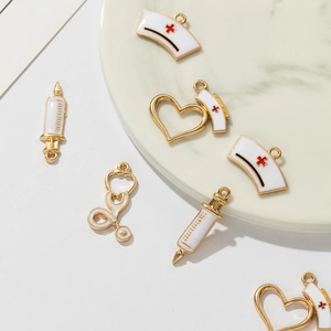 Detail of medical charms featuring nurse hat, syringe and stethoscope in gold enamel