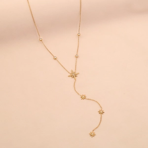 Detail of gold Y-shaped necklace with eight-pointed star pendants and inlaid diamonds