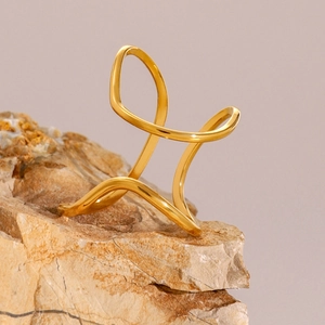 Macro view of 18k gold plated stainless steel crisscross ring on textured stone