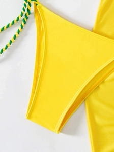 Detail view of yellow bikini bottoms featuring green and yellow braided side ties