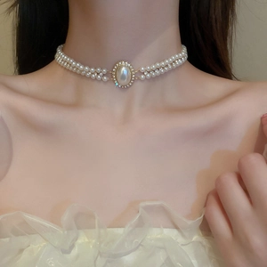 Gros plan d'un collier de perles baroques à double rangée avec pendentif ovale brillant