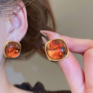 Detail of amber resin square earring with gold metal frame and retro tortoiseshell texture